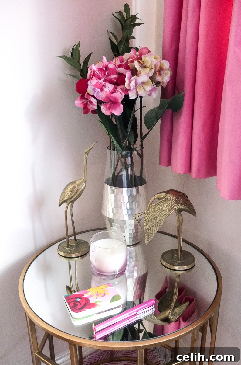 Styling a gold geometric table with a charming pink and gold theme, featuring flowers, a candle, and elegant brass cranes in a guest bedroom setting