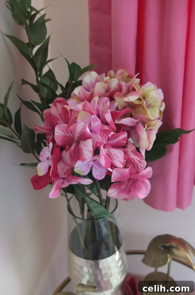 Gorgeous faux pink hydrangeas creating a lovely and welcoming floral arrangement on the gold side table in a guest room