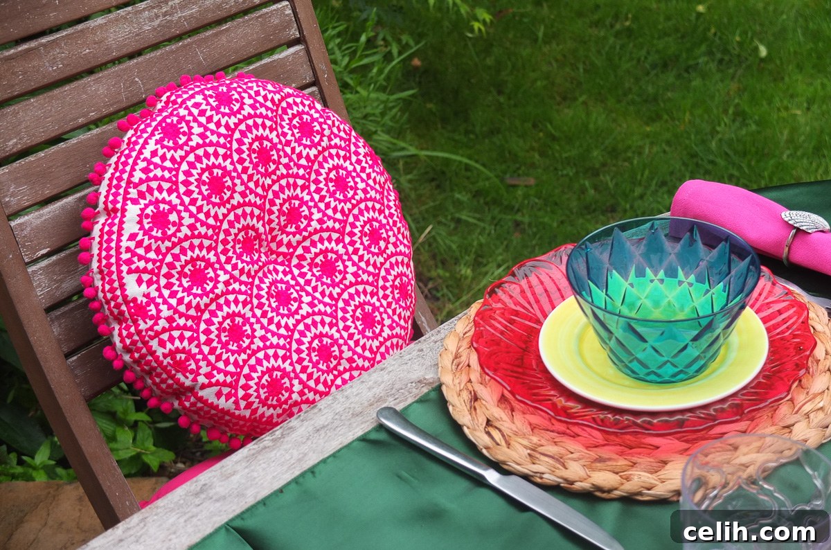 Gorgeous bright pink boho style round cushion with pompom trim from Sweetpea and Willow, perfect for outdoor decor.