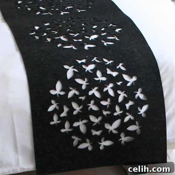 Close-up detail of the Selina Rose Bloom bed throw, highlighting the precise laser-cut pattern and the luxurious texture of the black wool felt