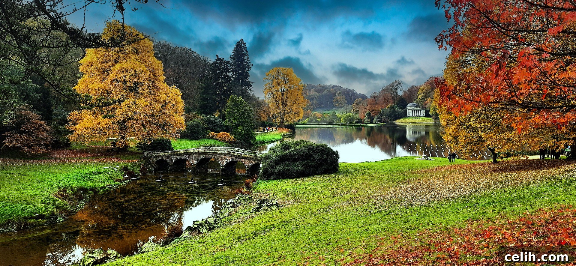 October's Golden Glow: Top Autumn Views Across the UK 2 A serene autumn scene at Stourhead, with a classical temple reflected in a calm lake surrounded by trees in fiery reds and shimmering yellows.